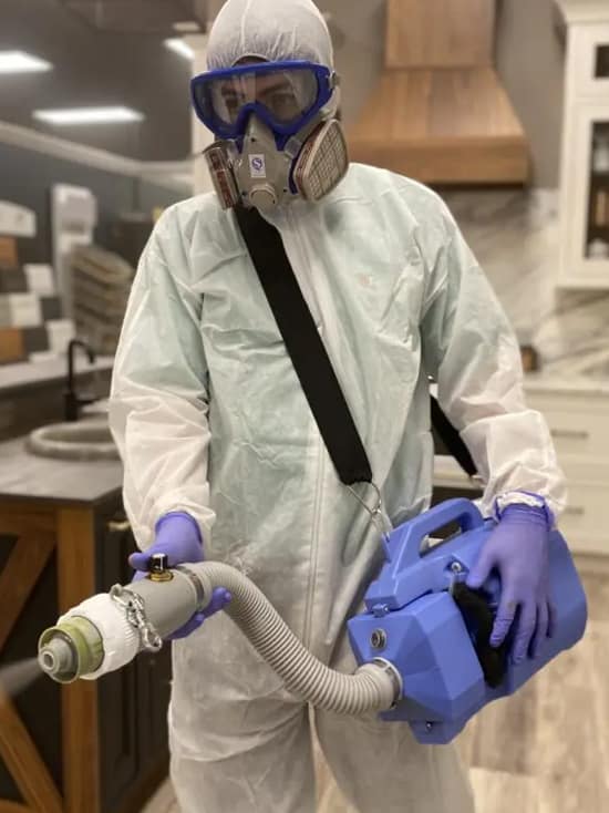 Cleaner with full PPE equipment doing disinfection service