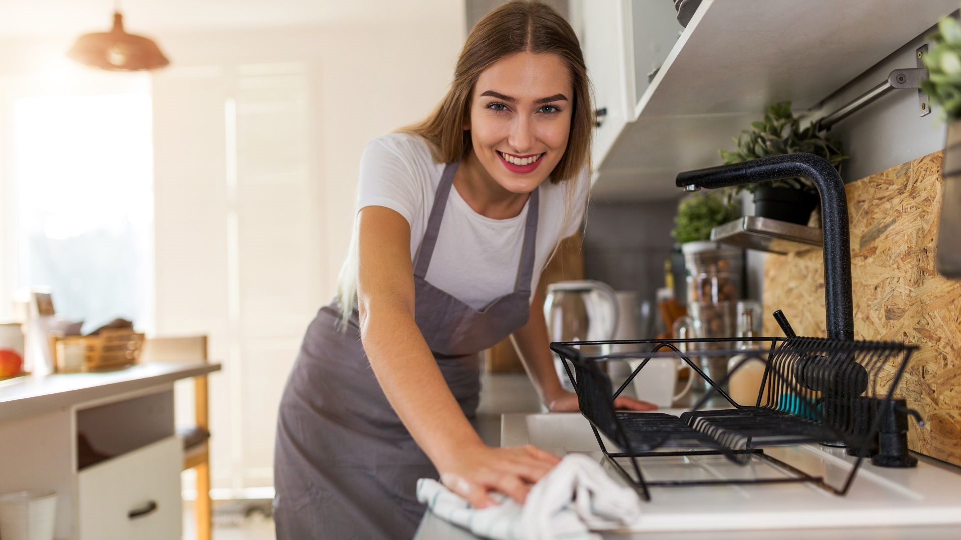 Lady cleaner cleaning the countertop of kitchen. book your first cleaning now